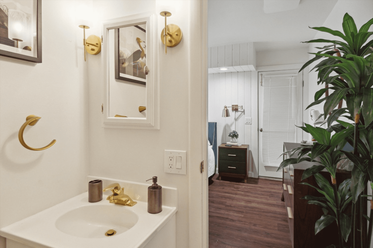 A bathroom with a sink , mirror , and plant.