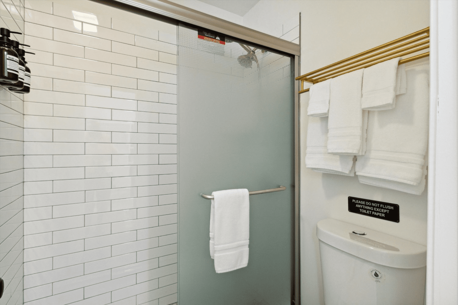 A bathroom with a toilet , shower , and towels.