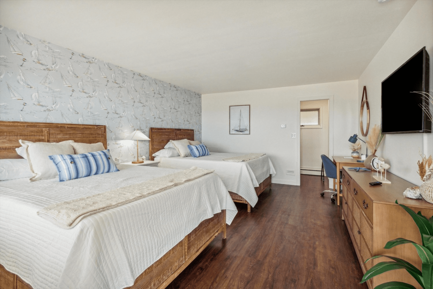 A hotel room with two beds , a desk , and a flat screen tv.