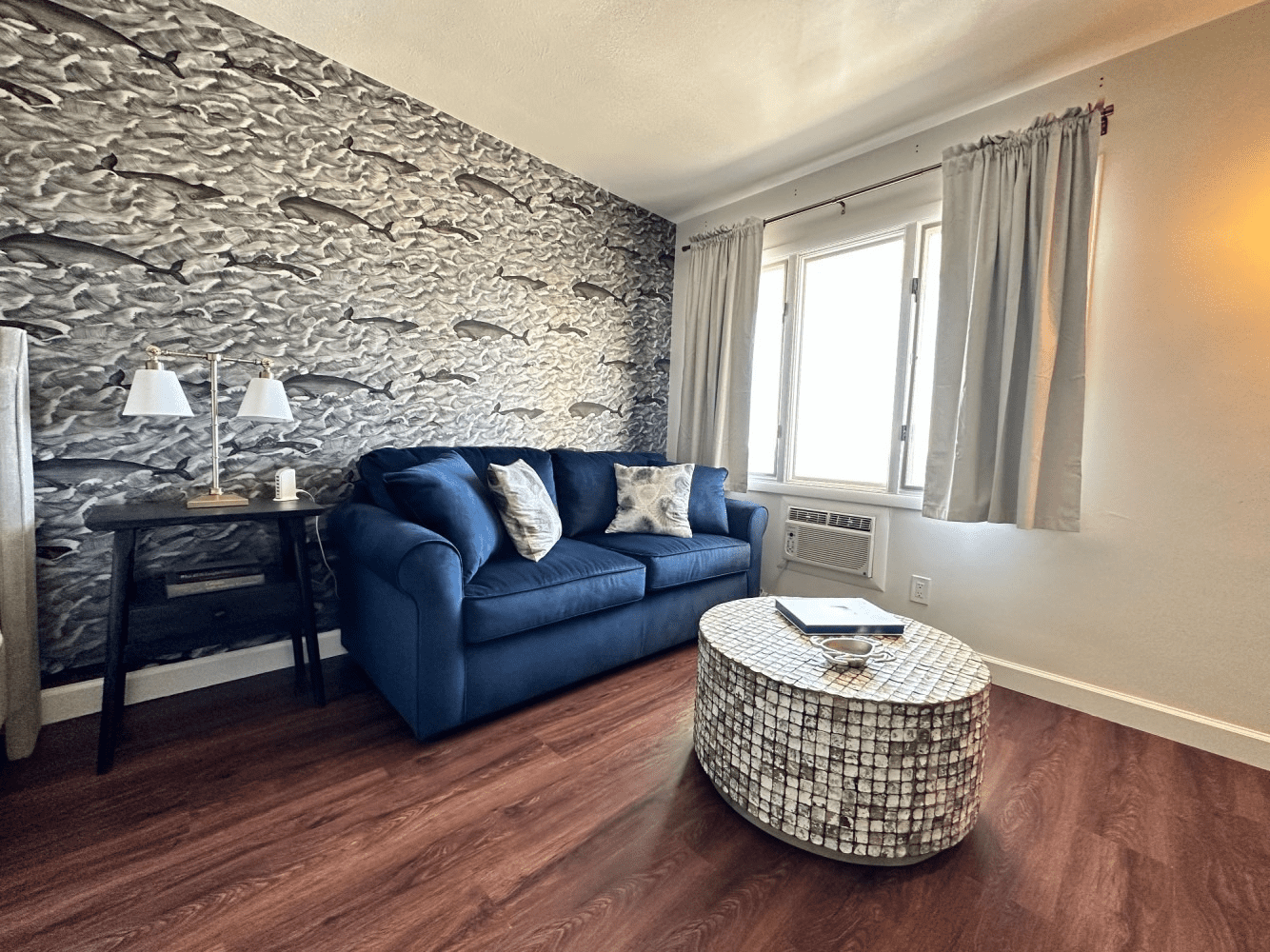 A living room with a blue couch and a round coffee table.