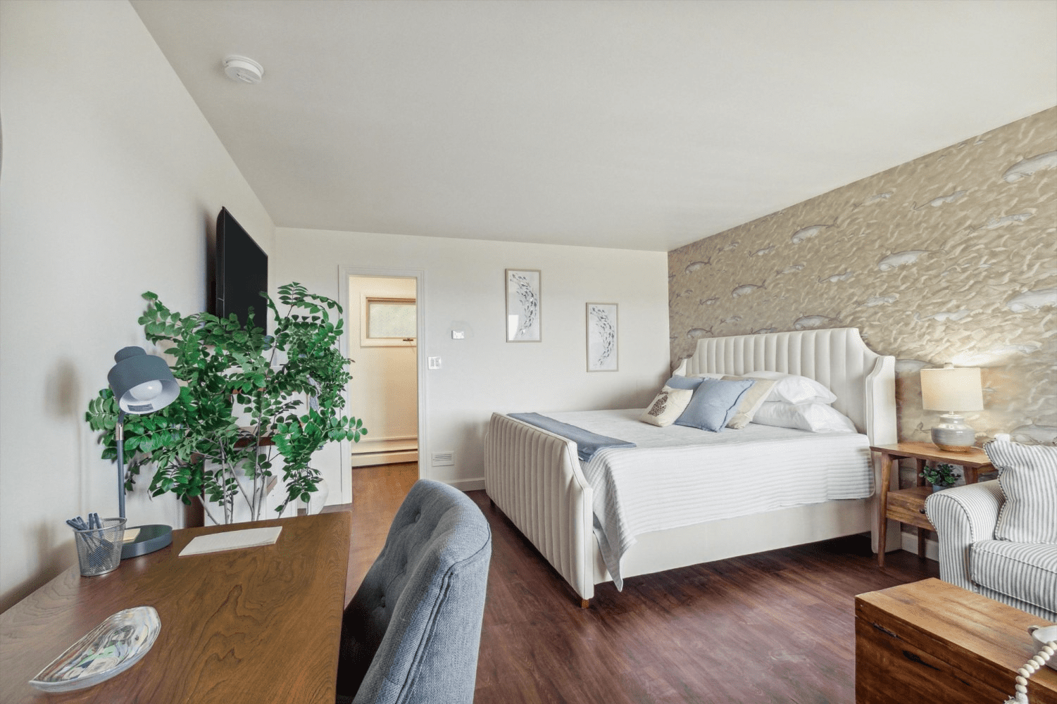 A bedroom with a large bed , desk , chair and television.