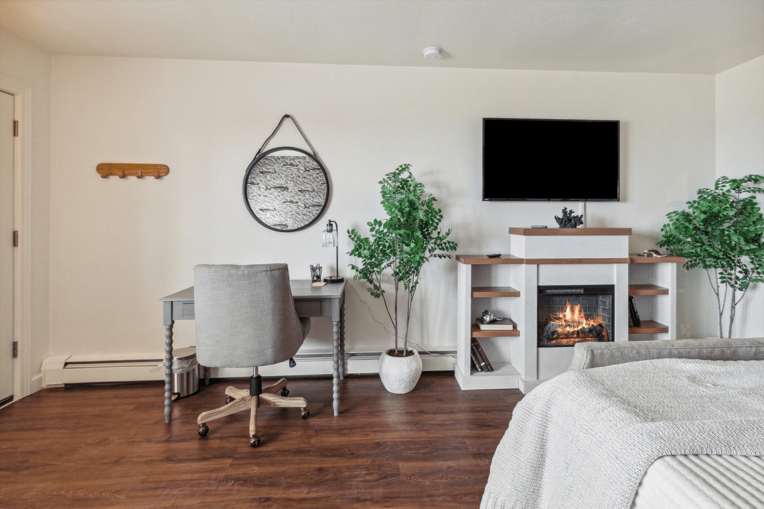 A living room with a desk , chair , television and fireplace.