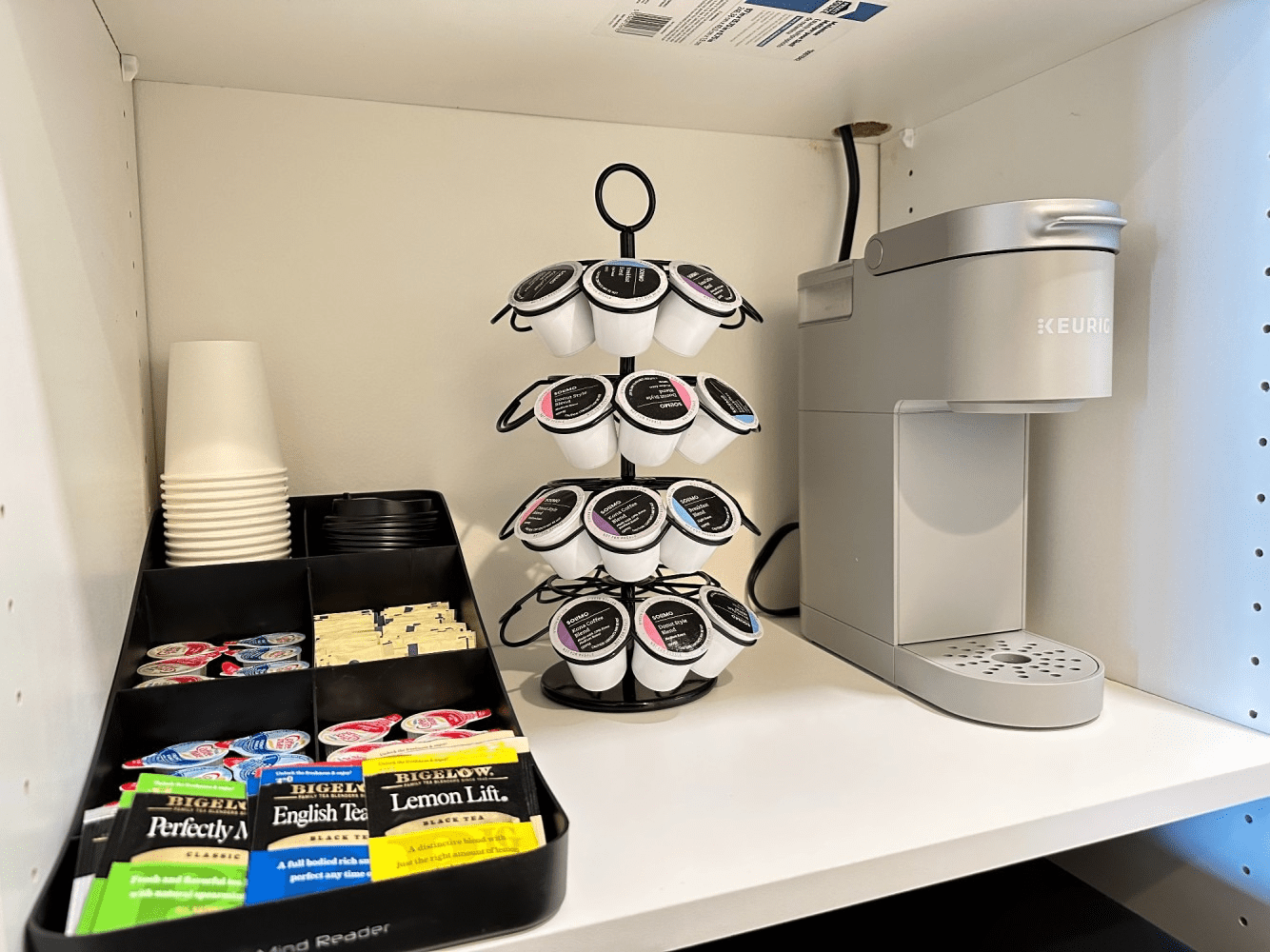 A coffee maker is sitting on a shelf next to a coffee cup holder.