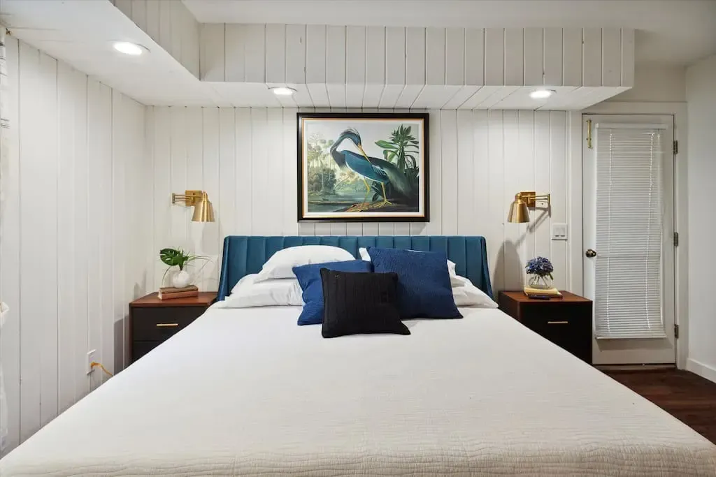 A bedroom with a large bed and a painting on the wall above it.