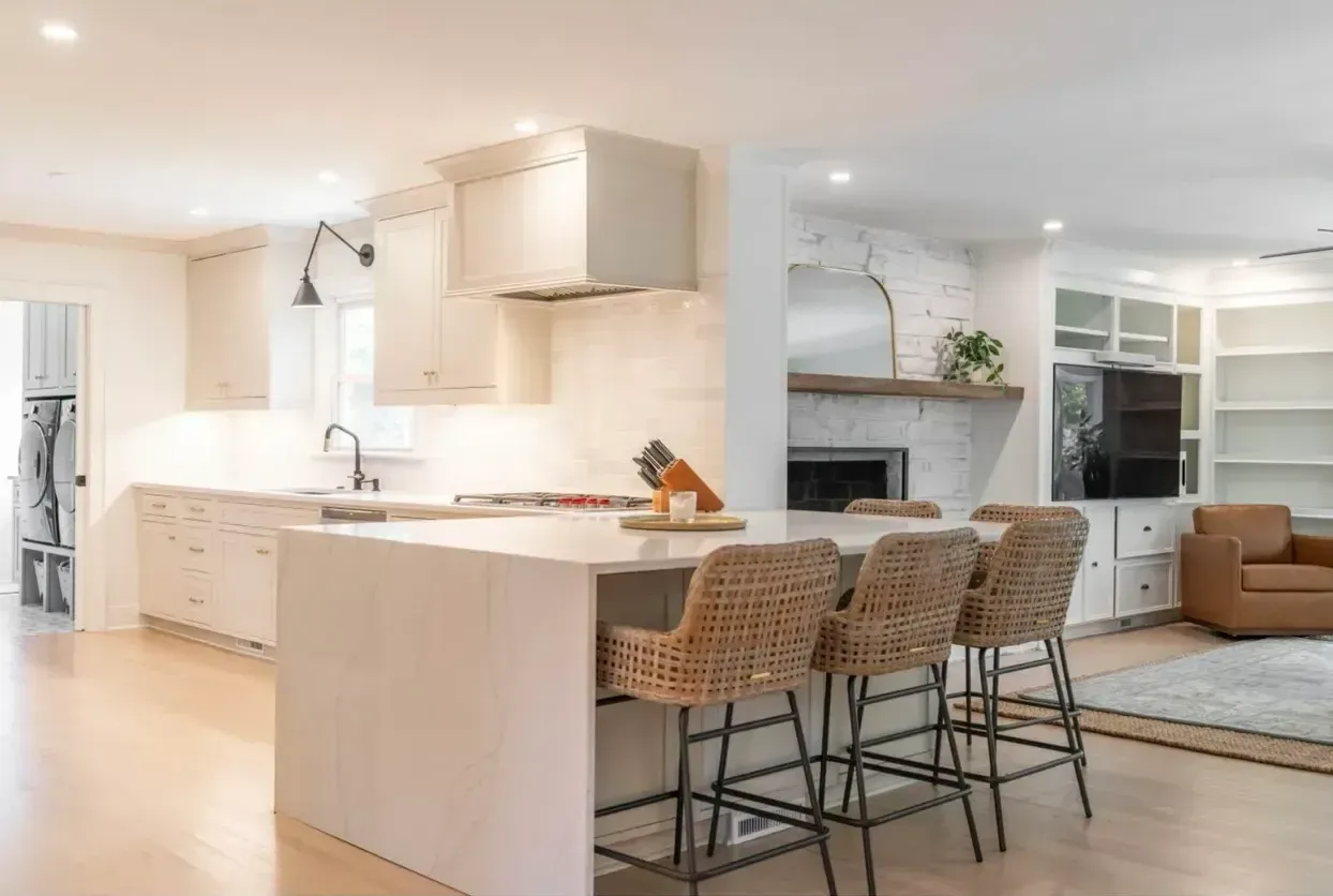 A kitchen with a large island and wicker chairs.