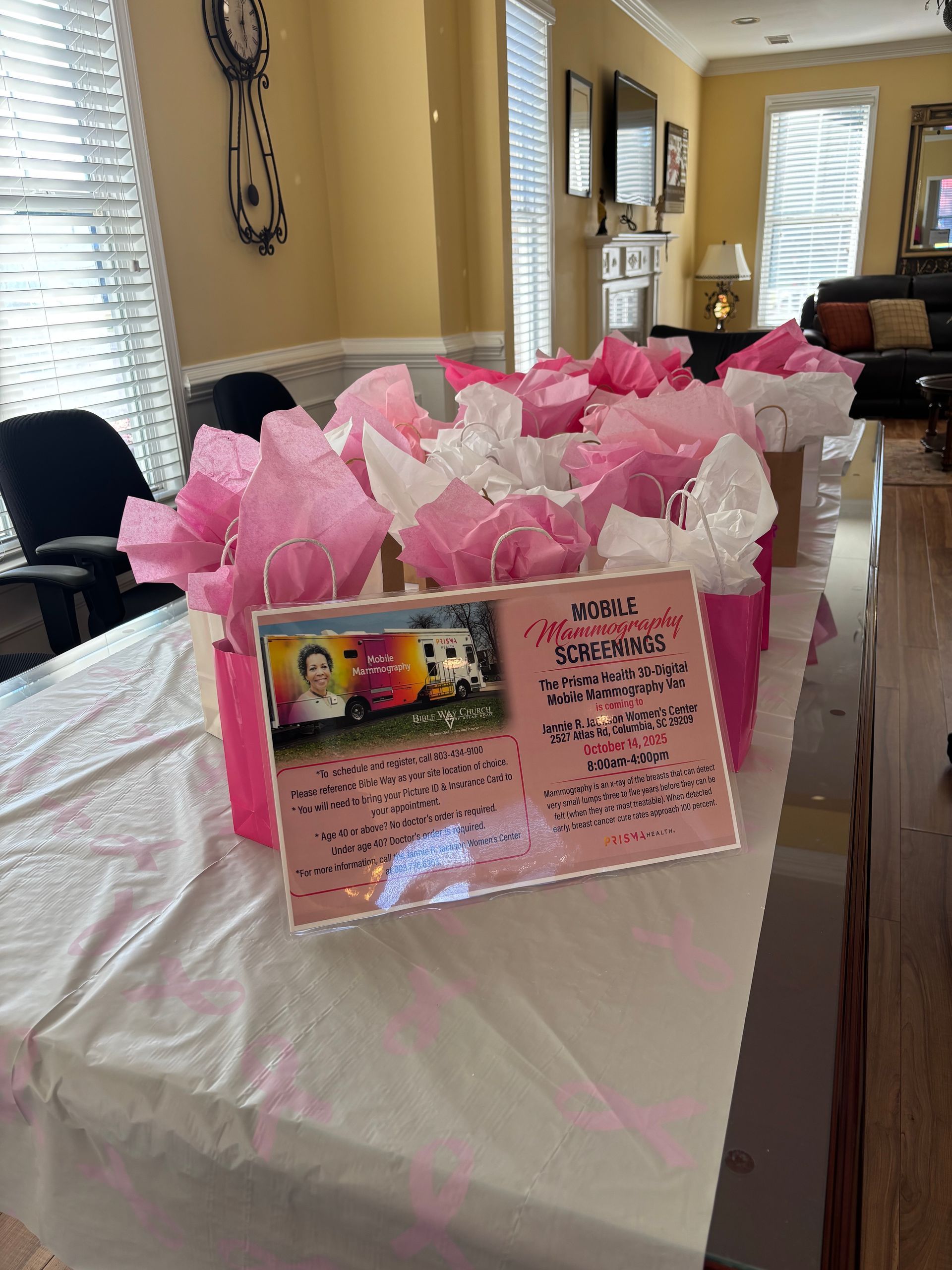 Gift table with pink and white tissue paper, photo, and sign in a room.