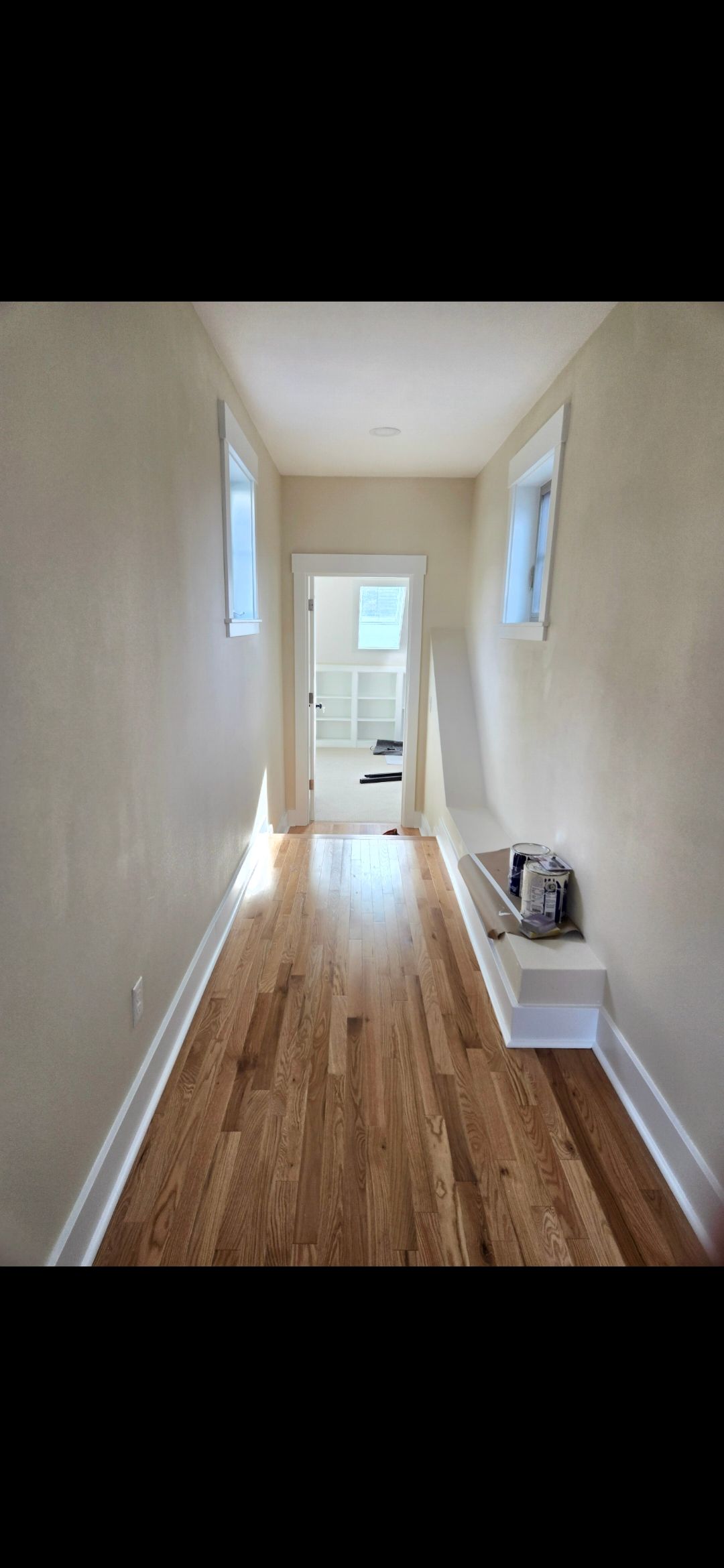 Ladders propped against a two-story house with dark brown siding; construction tools are on the ground.