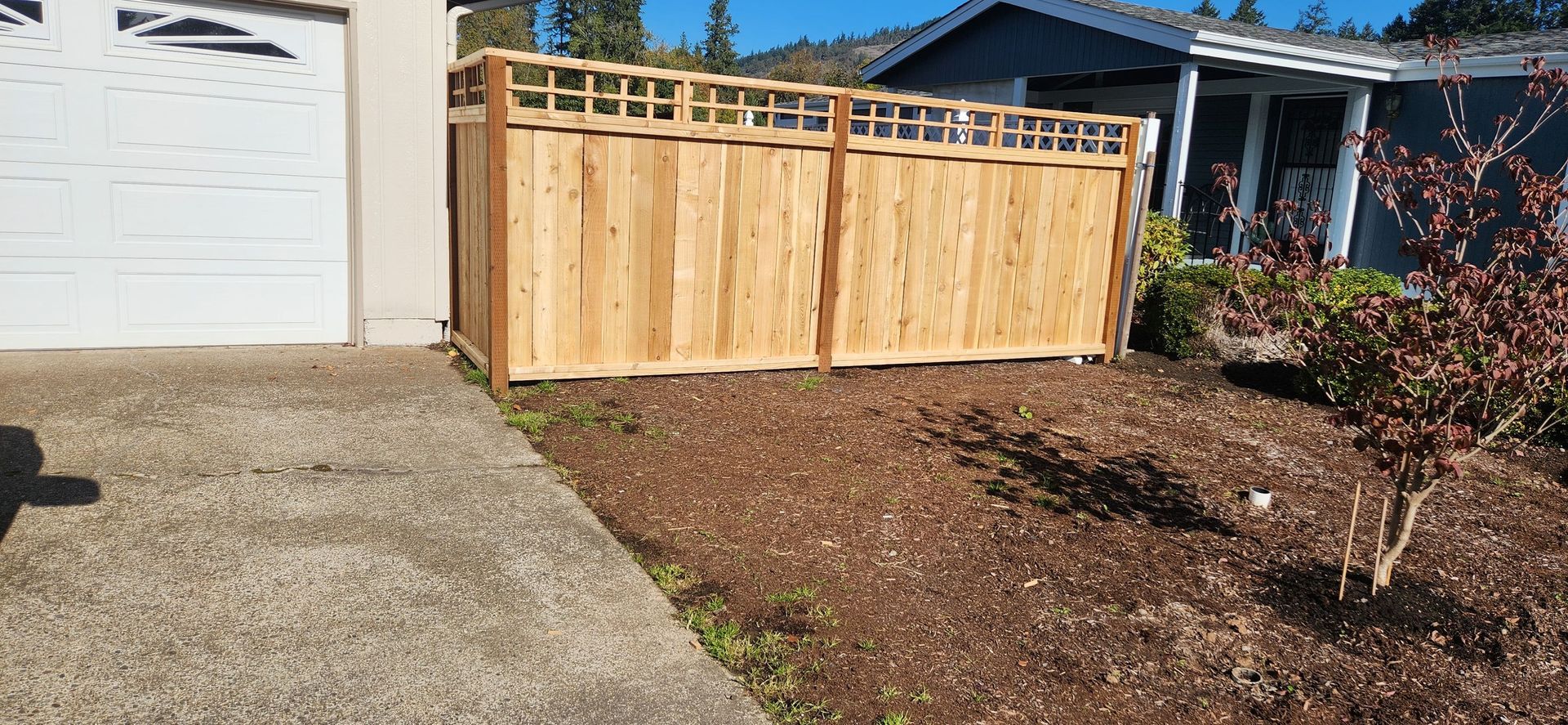 Deck with redwood railings under construction next to a green-sided house. Tools and materials are visible.