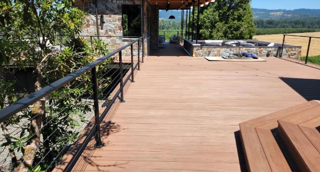 Backyard deck with wooden deck, and a green house with a sliding door.