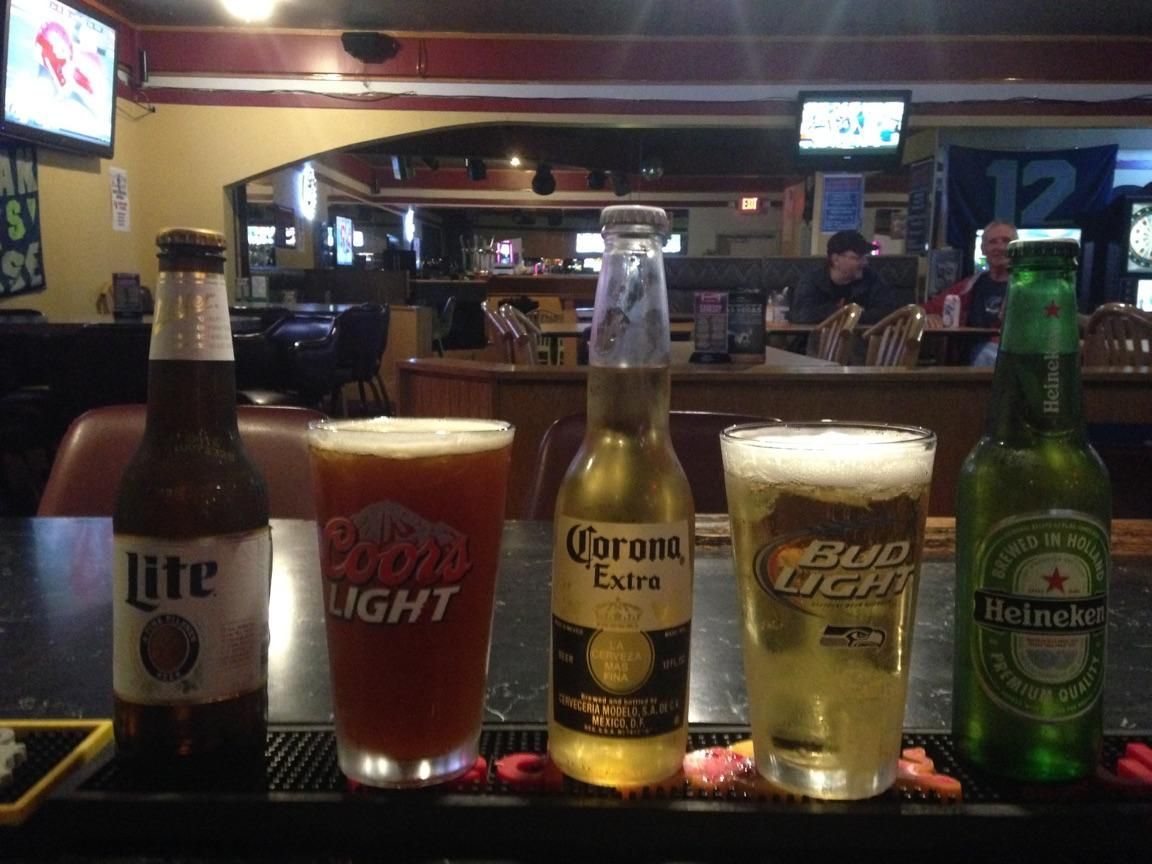A row of beer bottles including corona, bud light and heineken