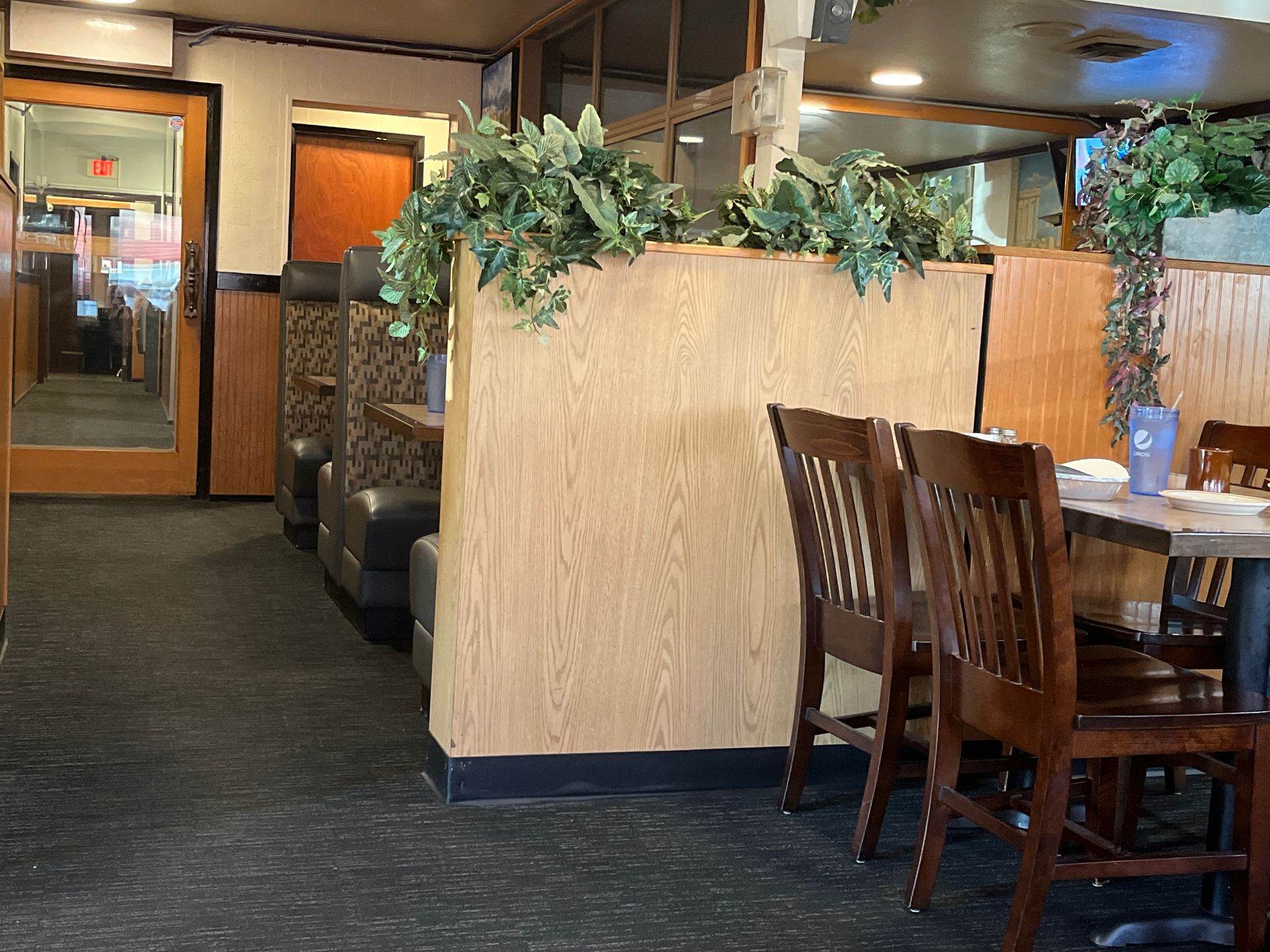 A restaurant with tables and chairs and a wooden wall.