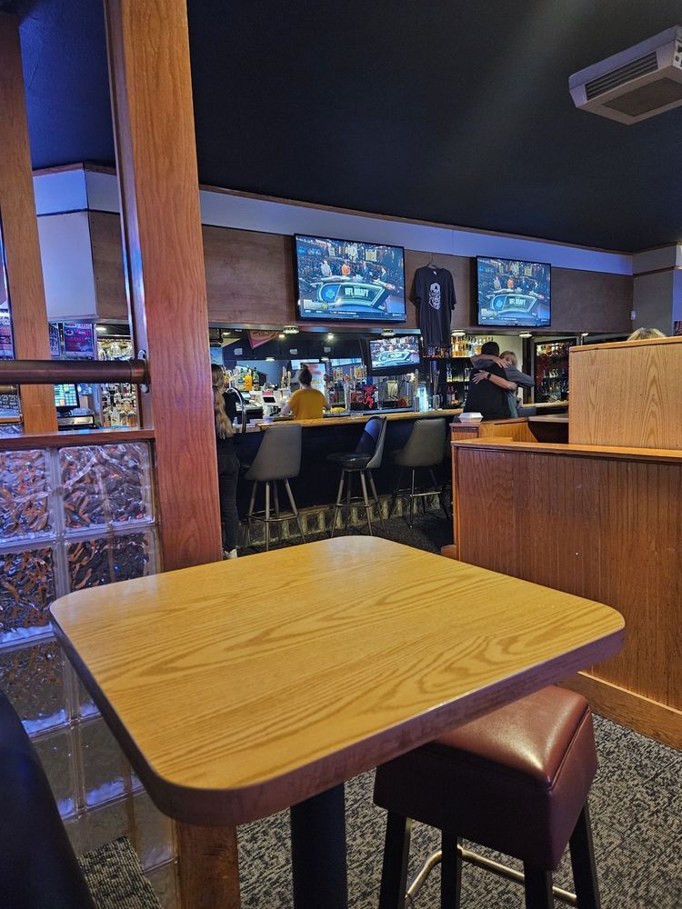 A wooden table in a restaurant with a bar in the background.