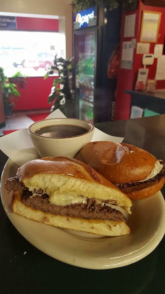 A French Dip sandwich and au jus on a plate on a table.