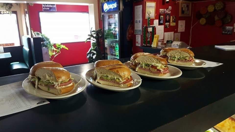 A row of sandwiches on plates on a counter in a restaurant.