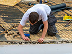 a man is kneeling on the ground working on a roof .