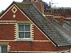a red brick house with a gray roof and a window .