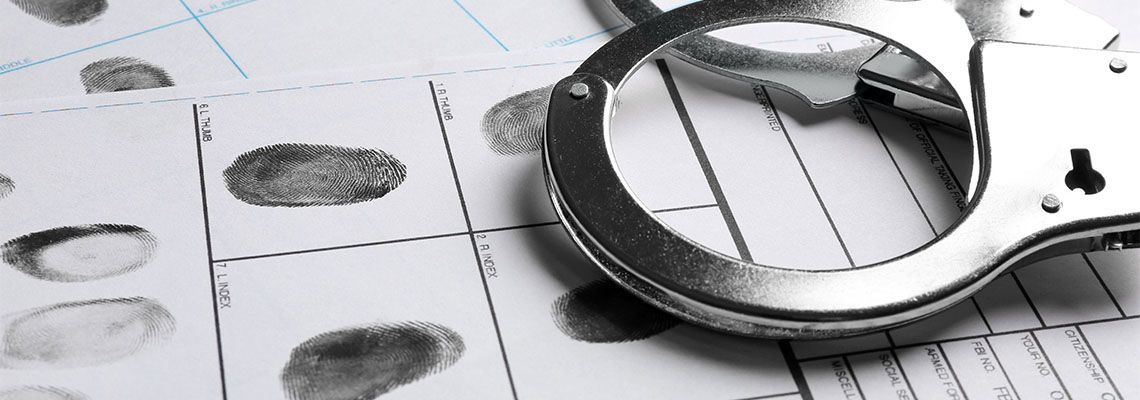 Handcuffs resting on a fingerprint form, possibly at a crime scene.