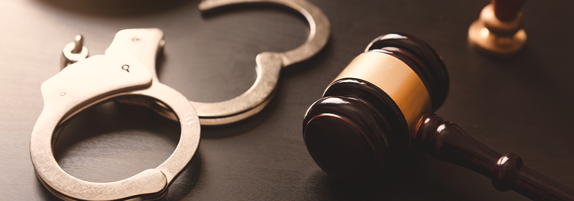Handcuffs and a gavel on a dark surface, suggesting legal or criminal justice themes.