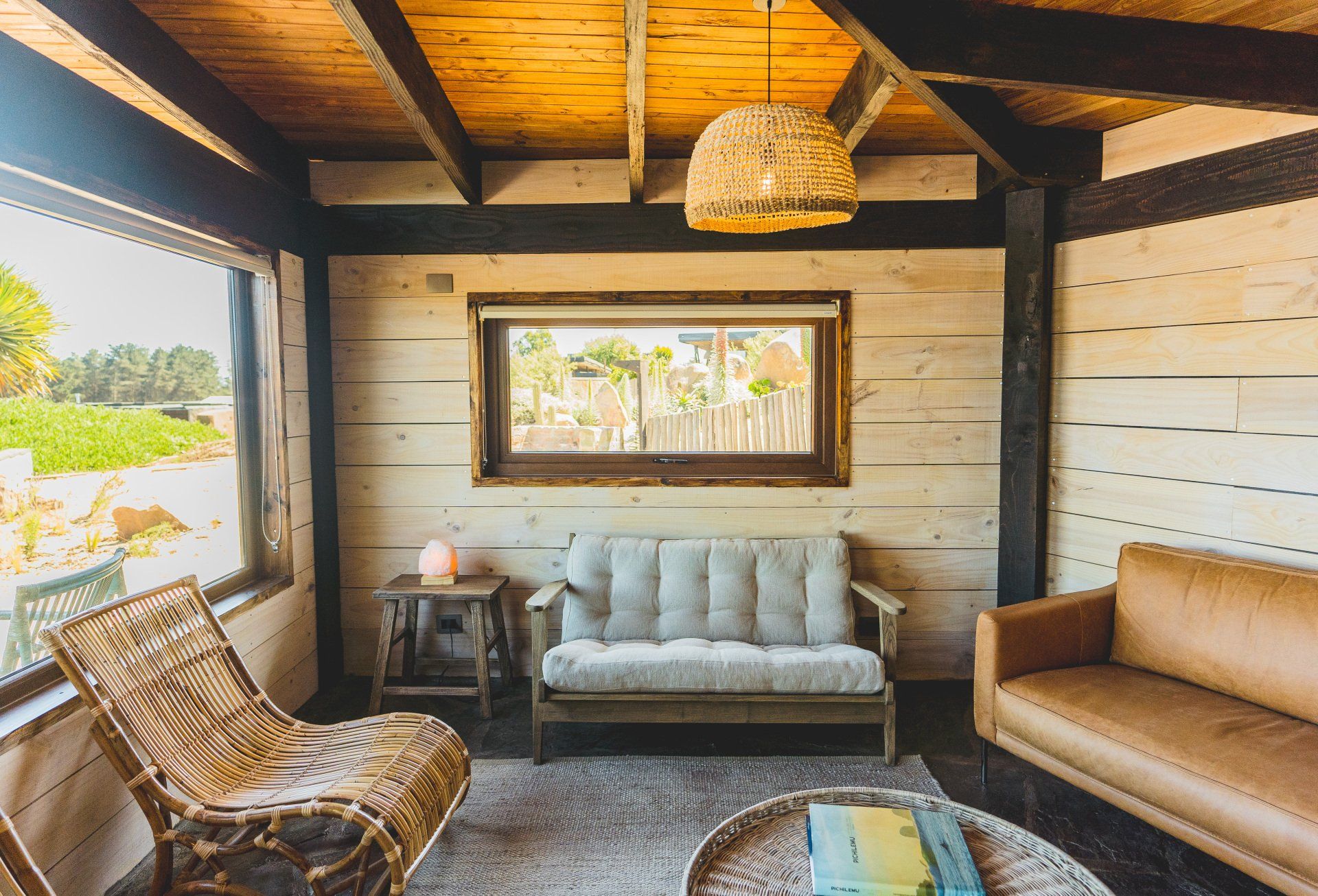 Cozy interior with wood paneled walls, wicker chair, leather sofa, and a natural woven lamp.