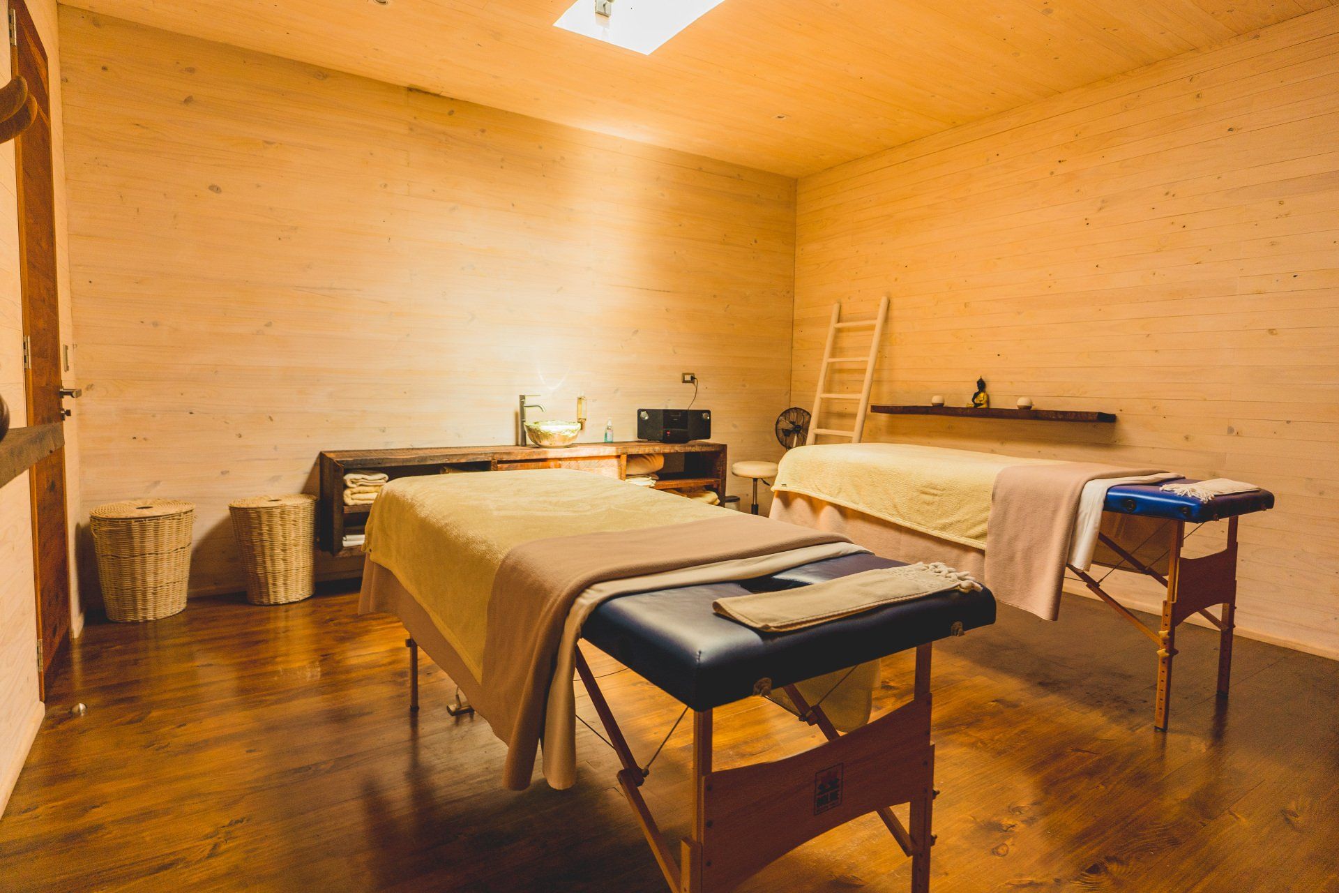 Massage room with two beds, wooden walls and floors.