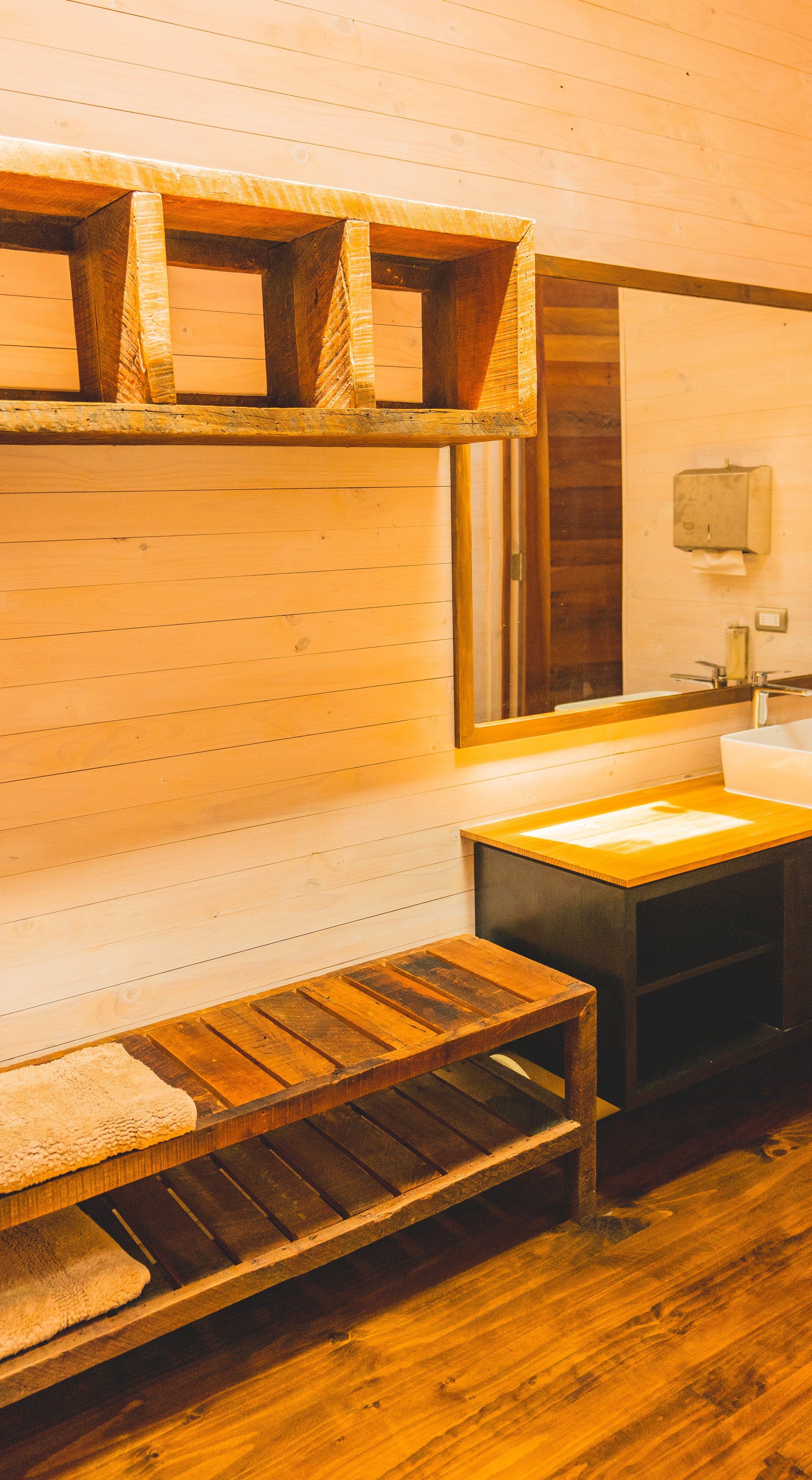 Rustic bathroom with wooden shelves, mirror, and sink.