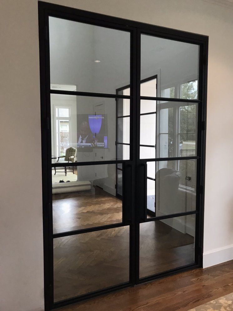 Black-framed glass French doors. Interior view. Reflects room with hardwood floors, white walls, and furniture.