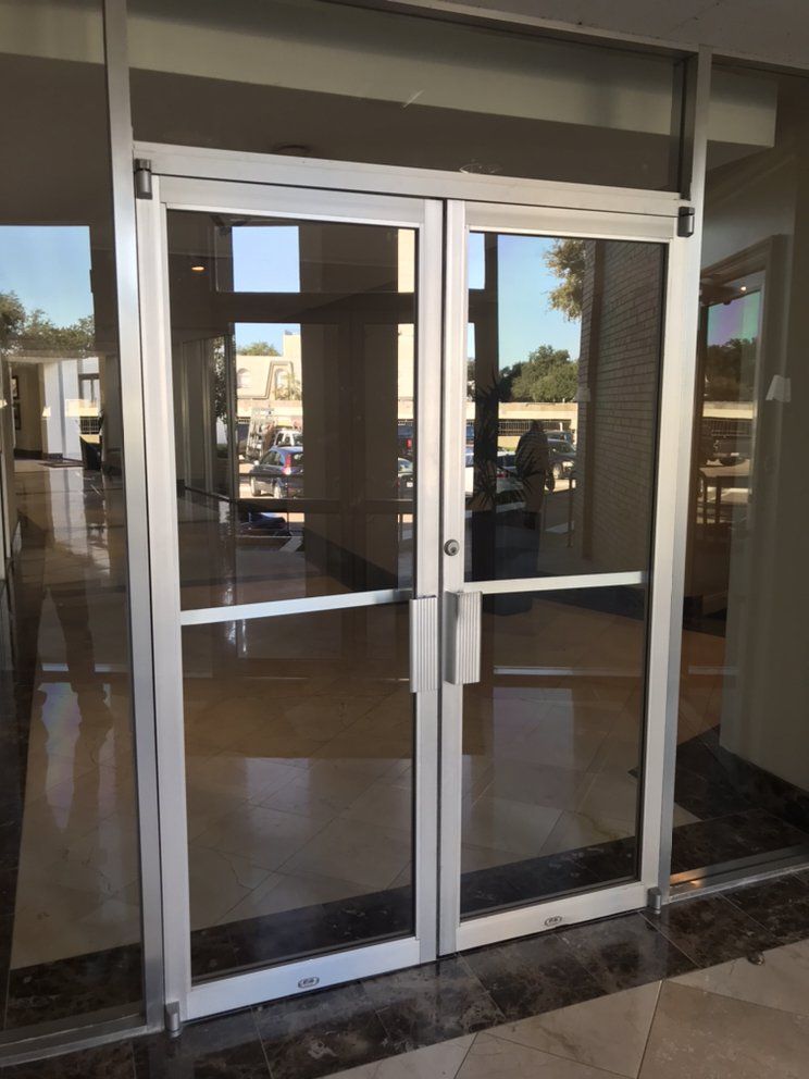 Glass double doors with silver frames leading into a building lobby.