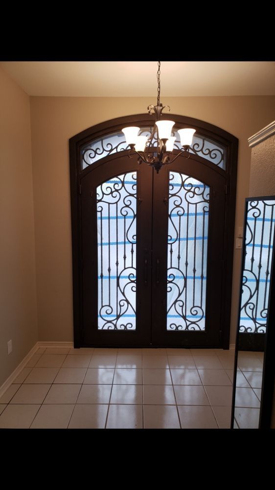 Dark brown double doors with ornate metalwork and a chandelier.
