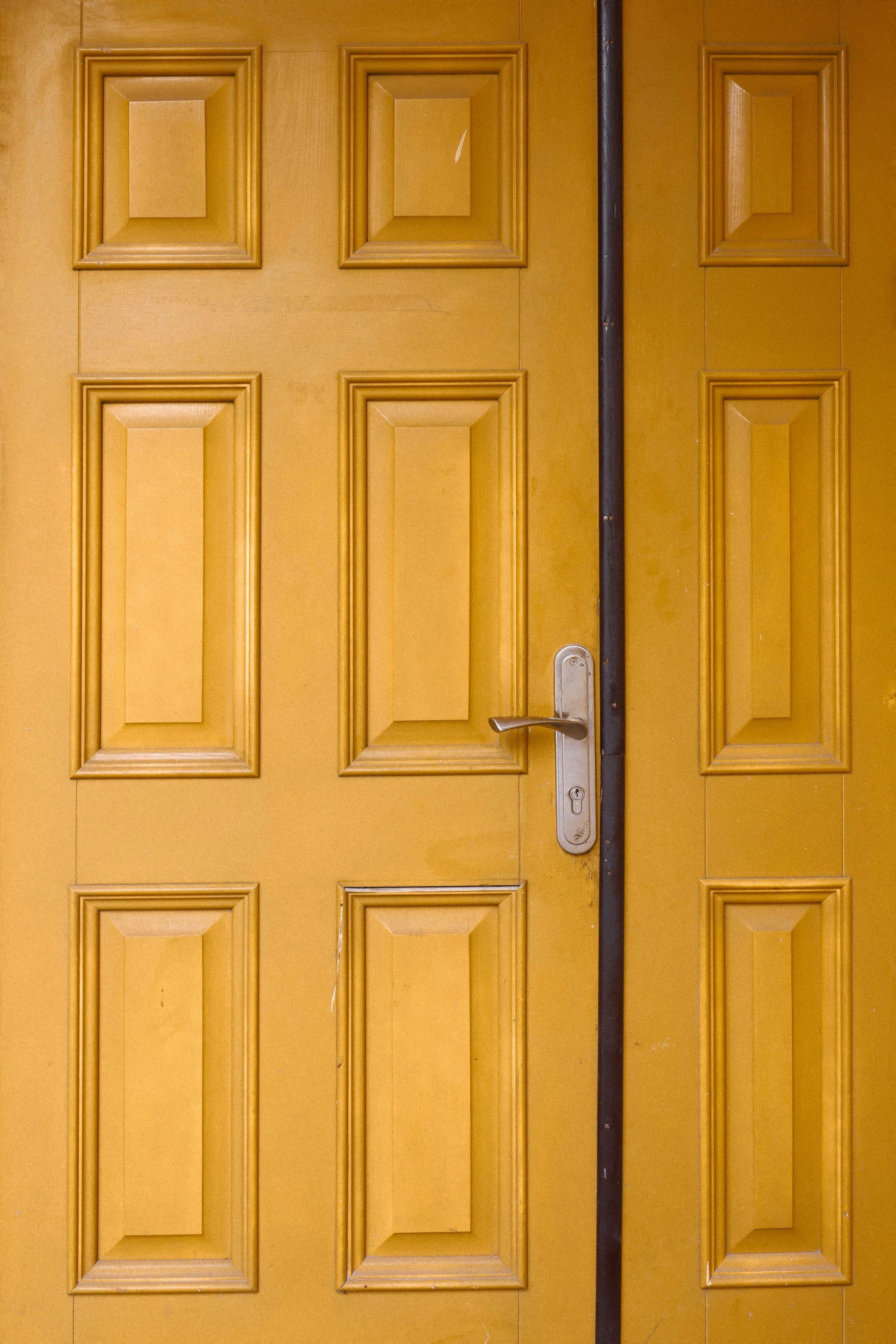 Yellow door with eight rectangular panels and a silver handle.