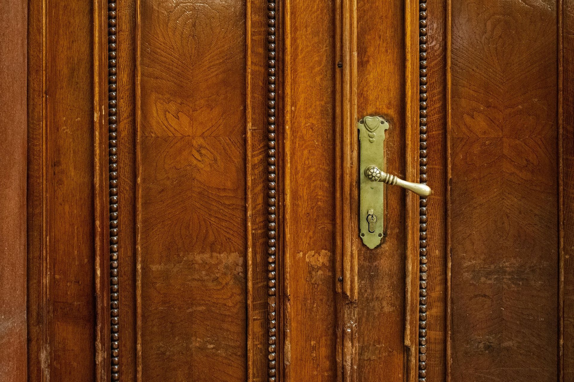 Wooden door with ornate brass handle.