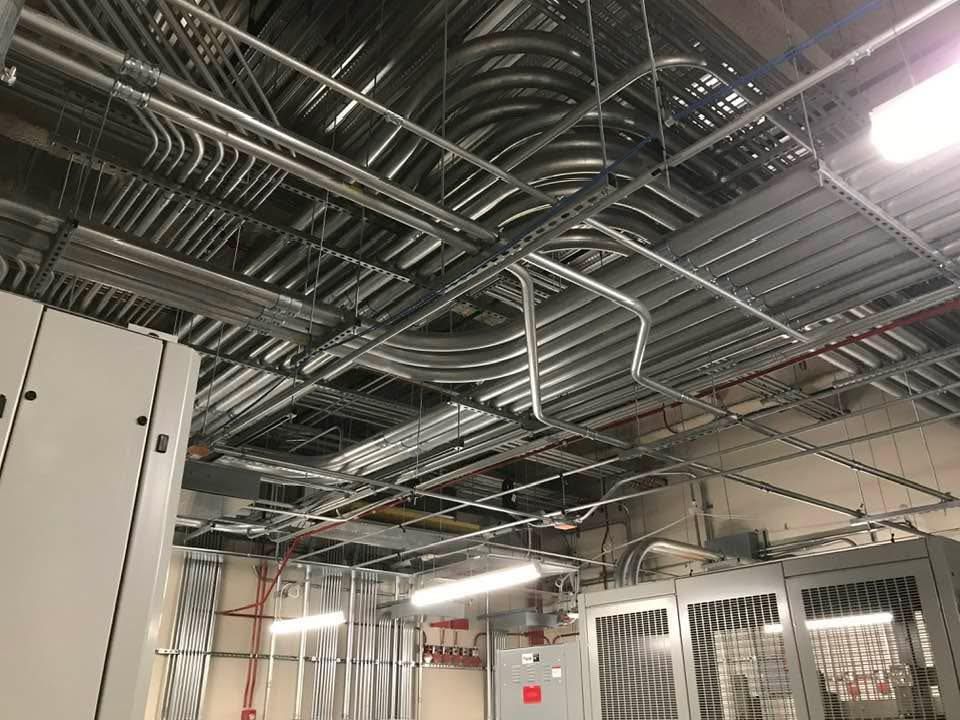 Electrical conduit network installed on a ceiling. Silver pipes in an industrial setting.