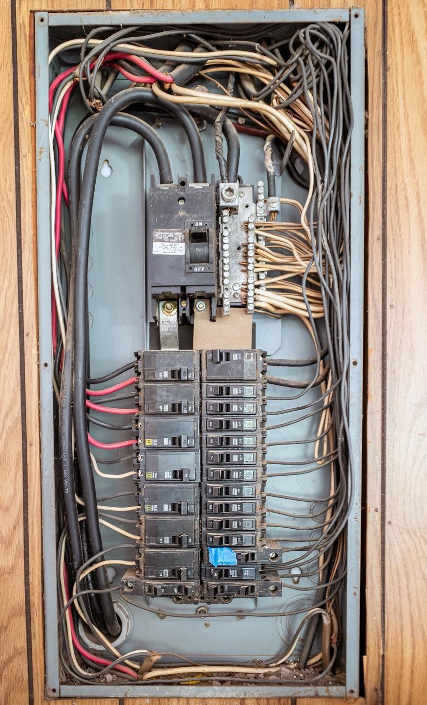 Electrical panel with numerous wires and circuit breakers.