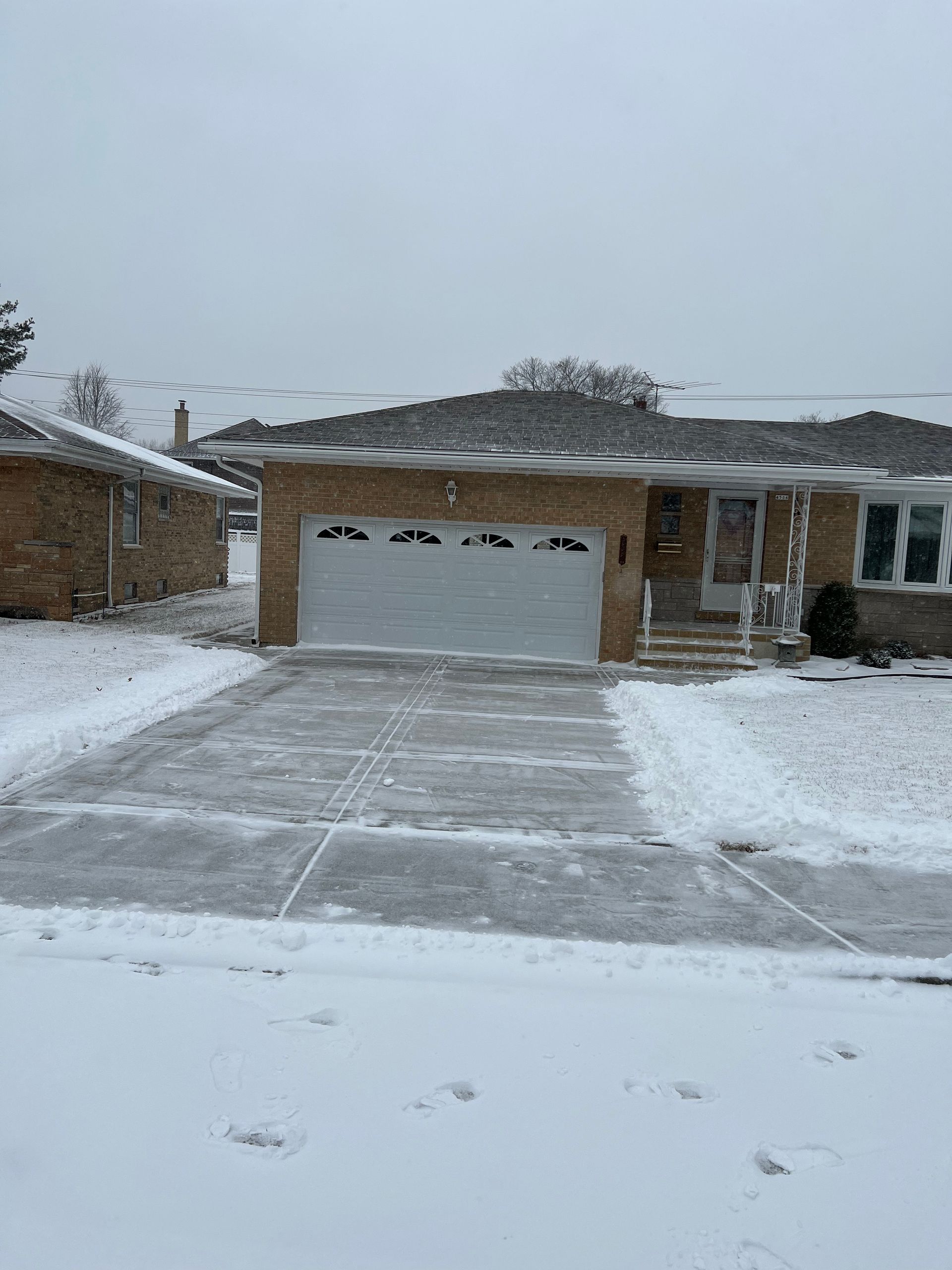 A house with a garage and a driveway covered in snow.
