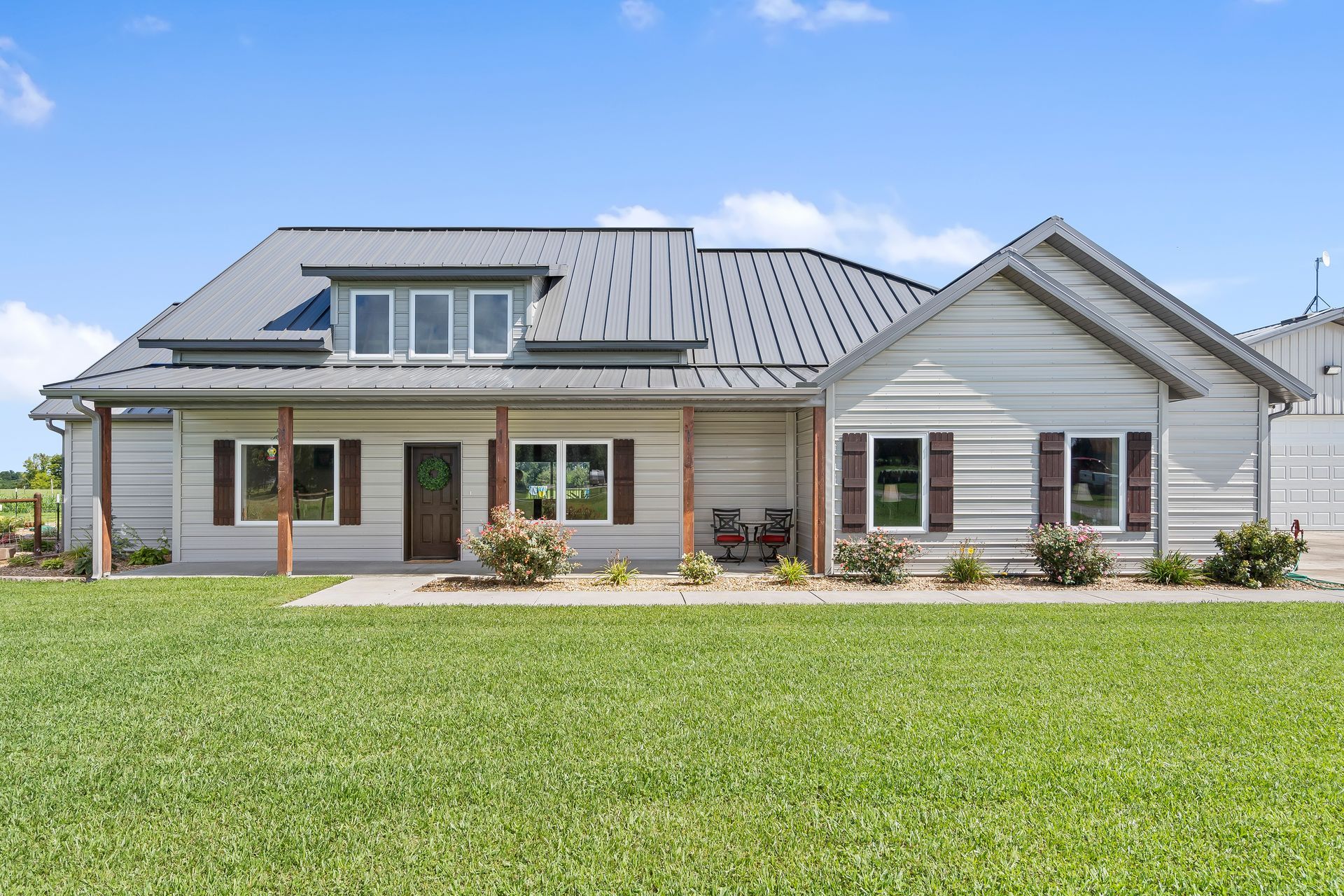 A large white house with a metal roof is sitting on top of a lush green field. | Eco-friendly home in MO