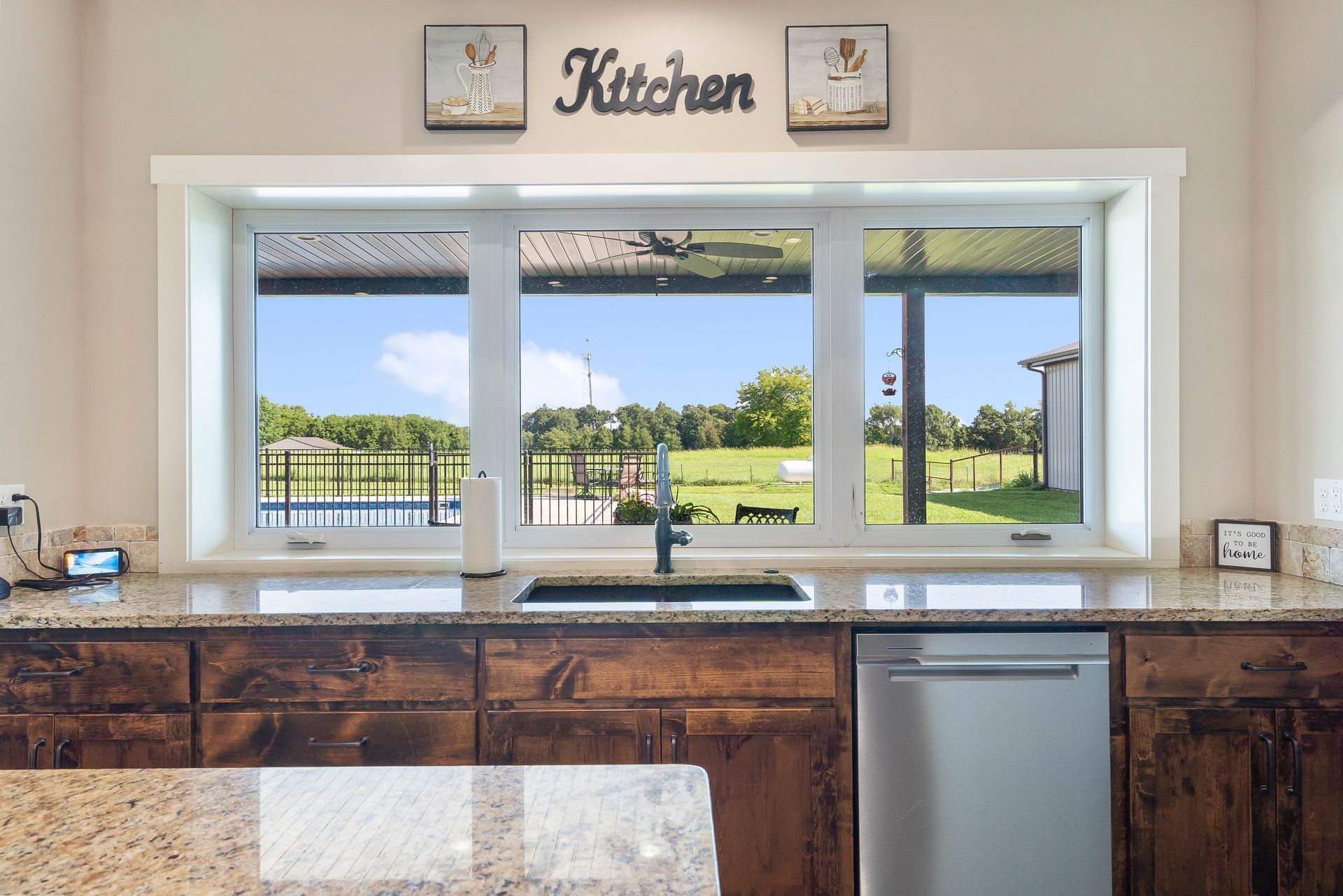 ICF kitchen with dark wood grain cabinets and granite countertops looking out over backyard with pool | Ozark, MO