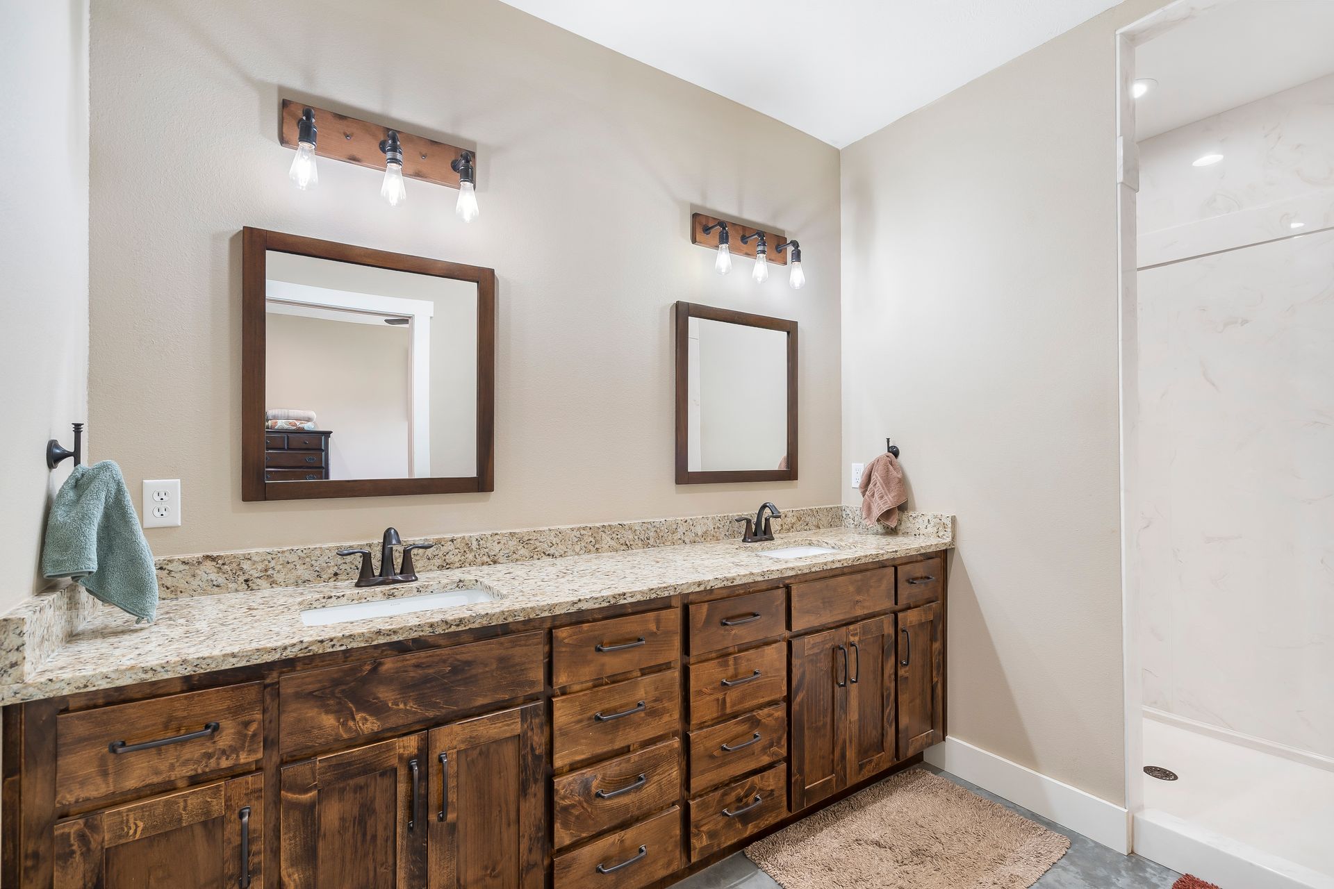 Bathroom with double vanity and granite countertops and walk-in shower in ICF custom home | Ozark, MO