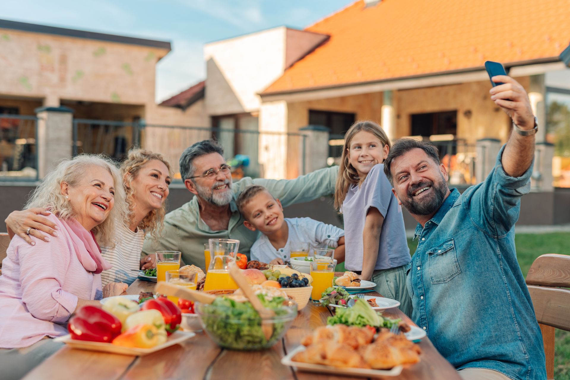 Multigenerational family smiling and taking photo in front of custom concrete home | Branson, MO