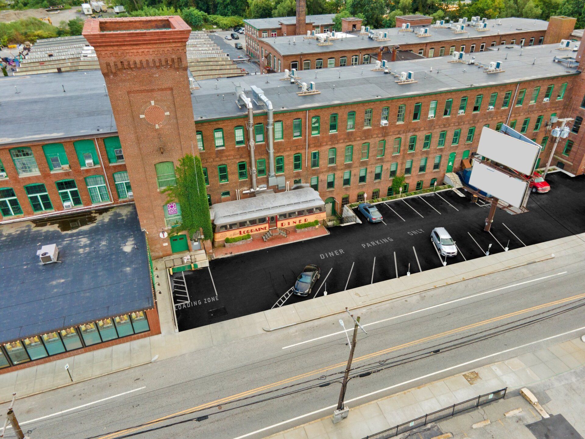 An aerial view of a large brick building with a parking lot in front of it