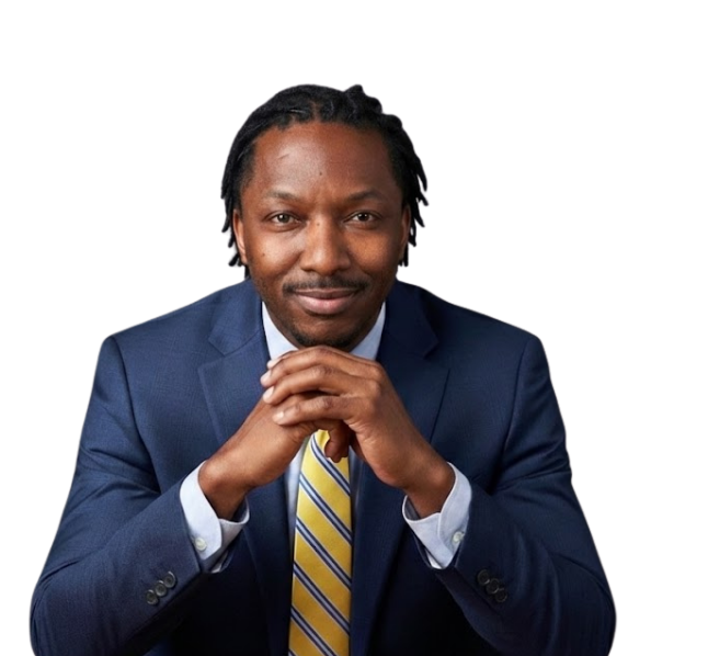 Man in a navy suit and yellow tie, resting his chin on clasped hands against a white background