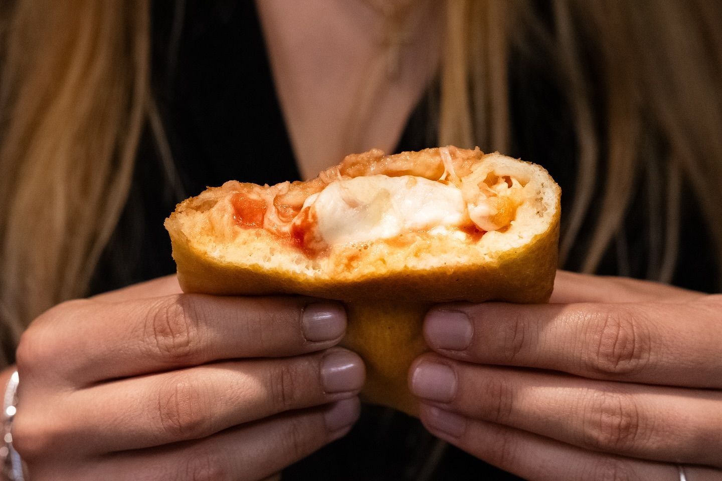 Una donna tiene in mano una fetta di pizza.