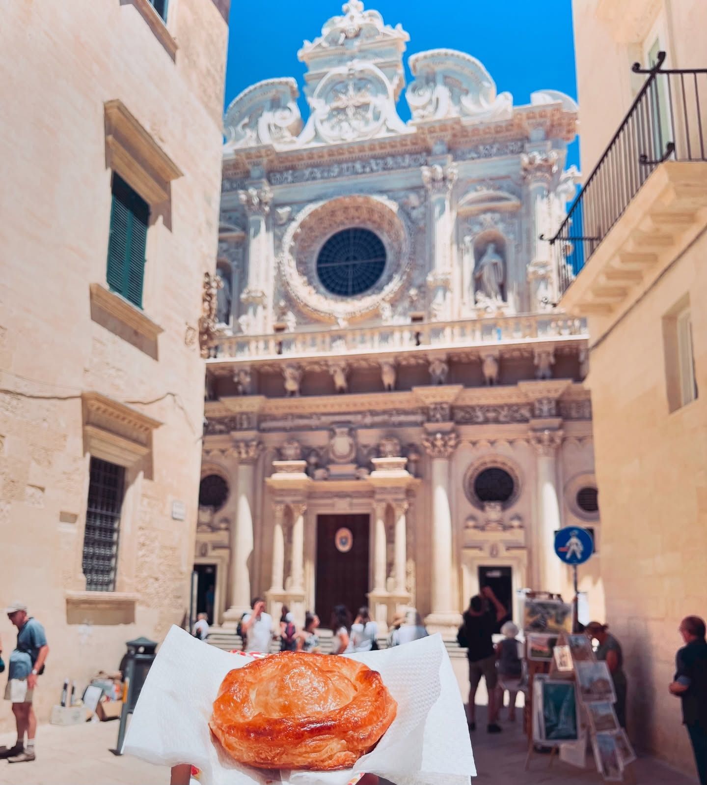 Una persona che tiene in mano un dolce davanti a un grande edificio