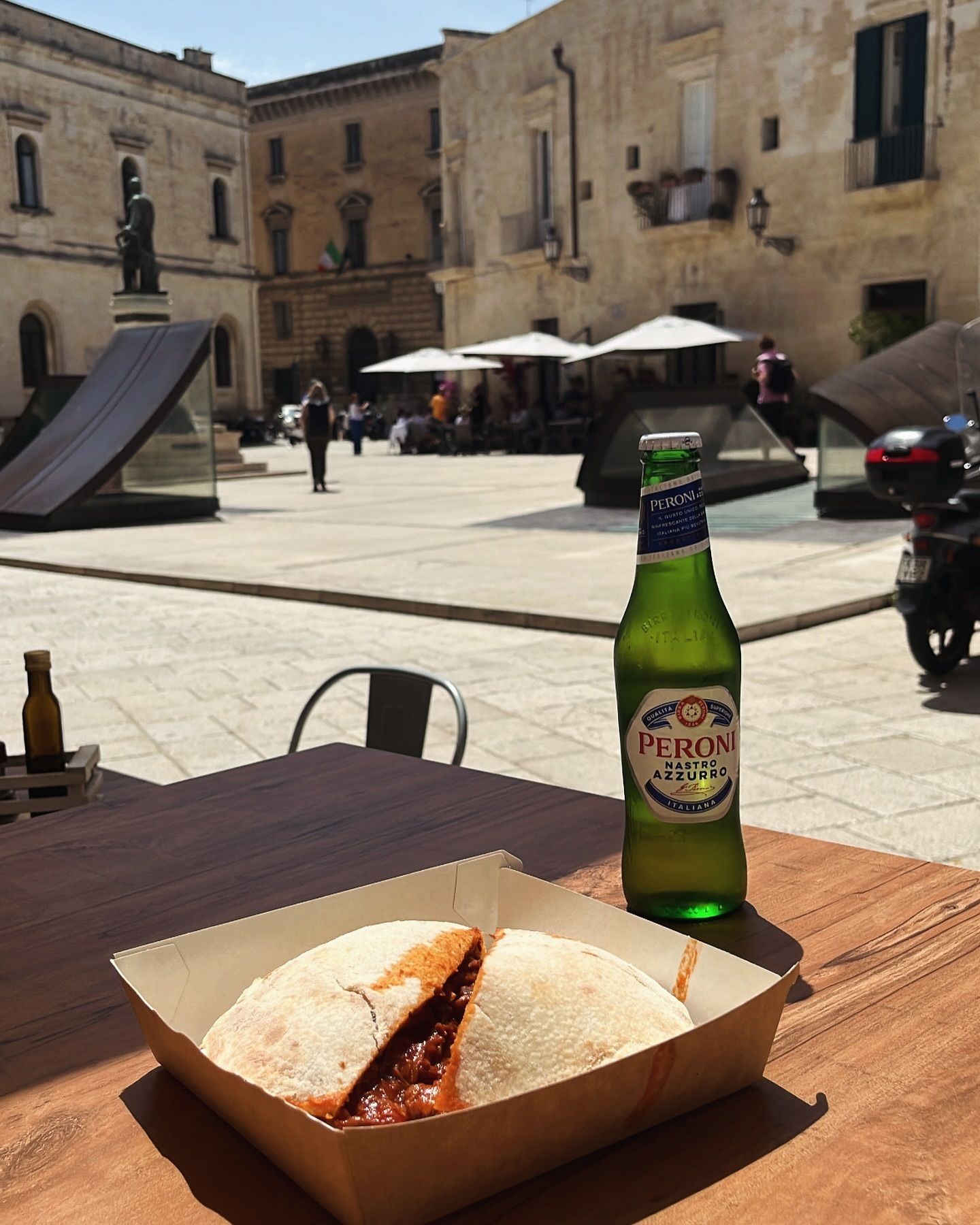 Una bottiglia di Peroni è appoggiata su un tavolo accanto a un panino