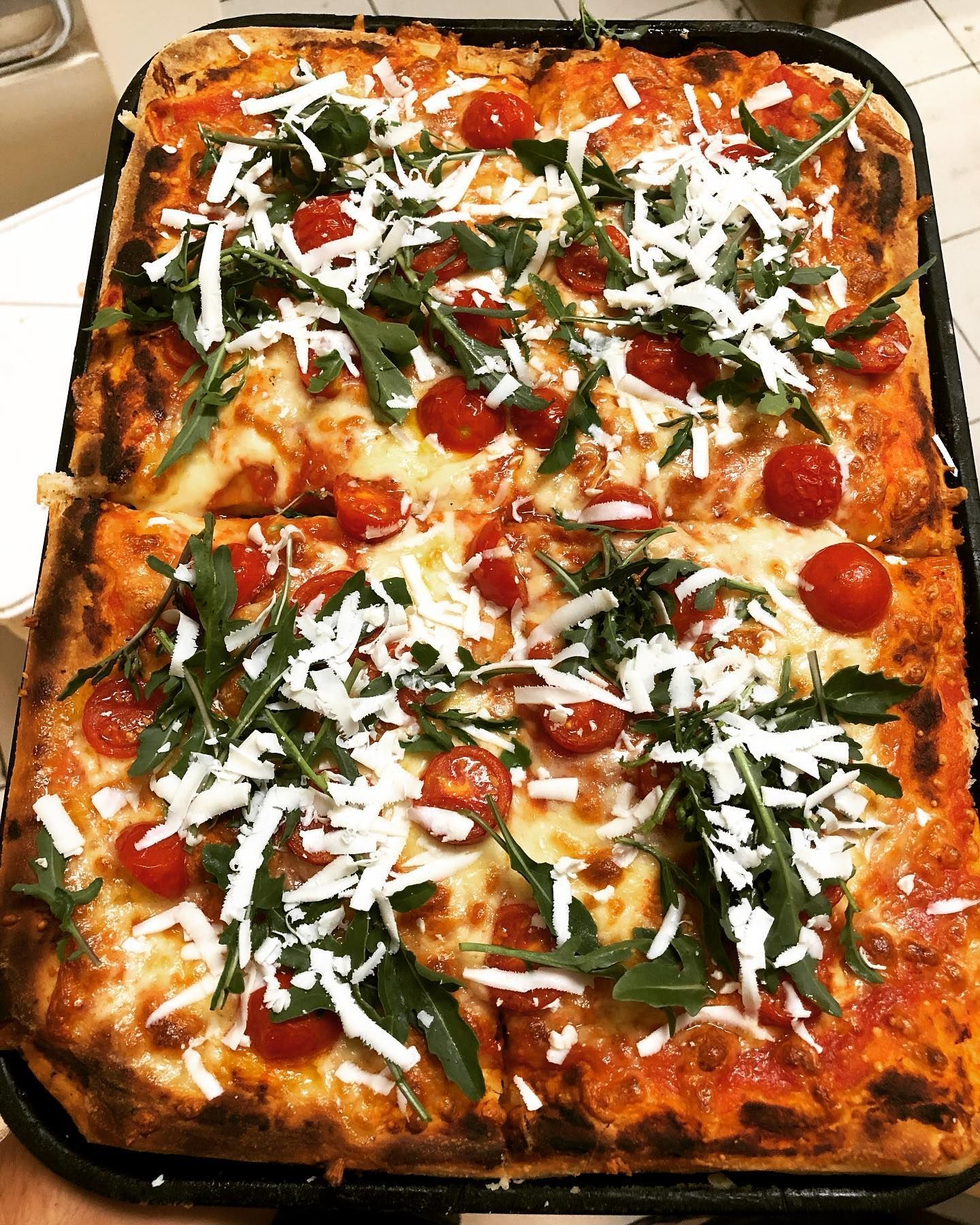 Una pizza con pomodori e formaggio è su una teglia.