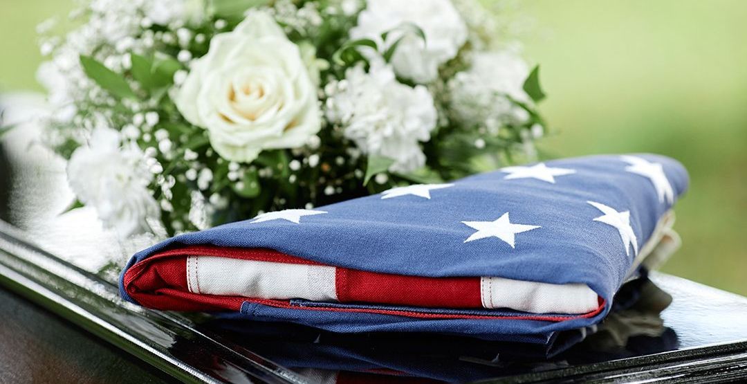 an american flag is laying on top of a coffin next to a bouquet of flowers .