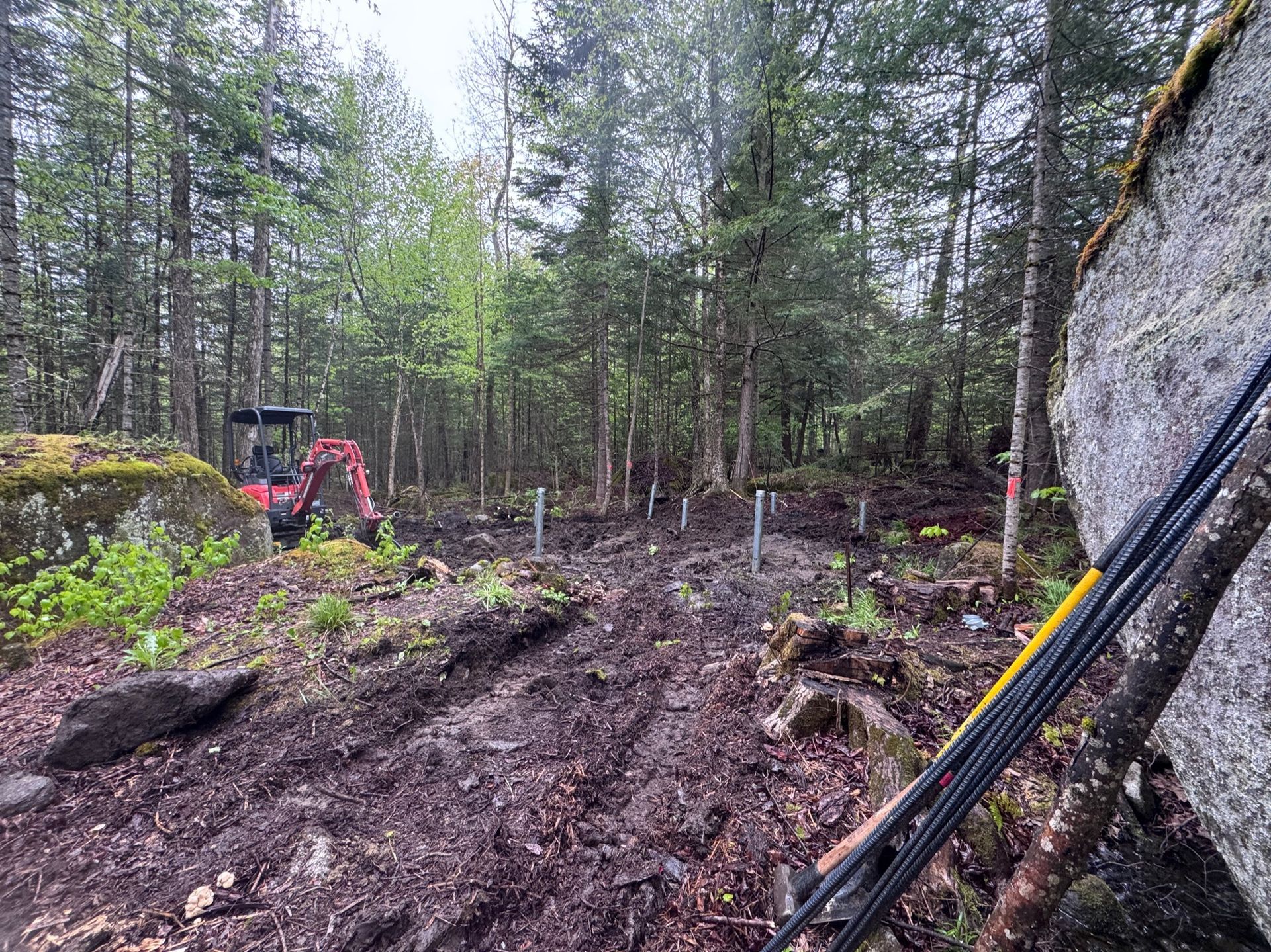 Placing metal piers in the woods at the future Quartz Cabin site at Stone City