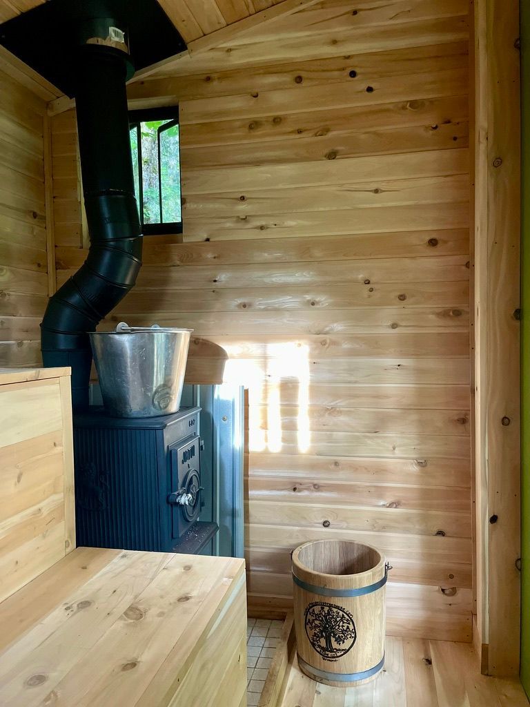 The Forest Sauna, with a heater and buckets next to the bench seat