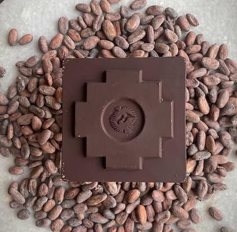 A chocolate bar is sitting on top of a pile of cocoa beans.