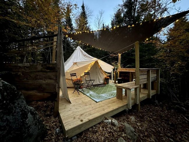 The Pebble Tent site - a canvas bell tent on a wooden platform with flowers and a table.