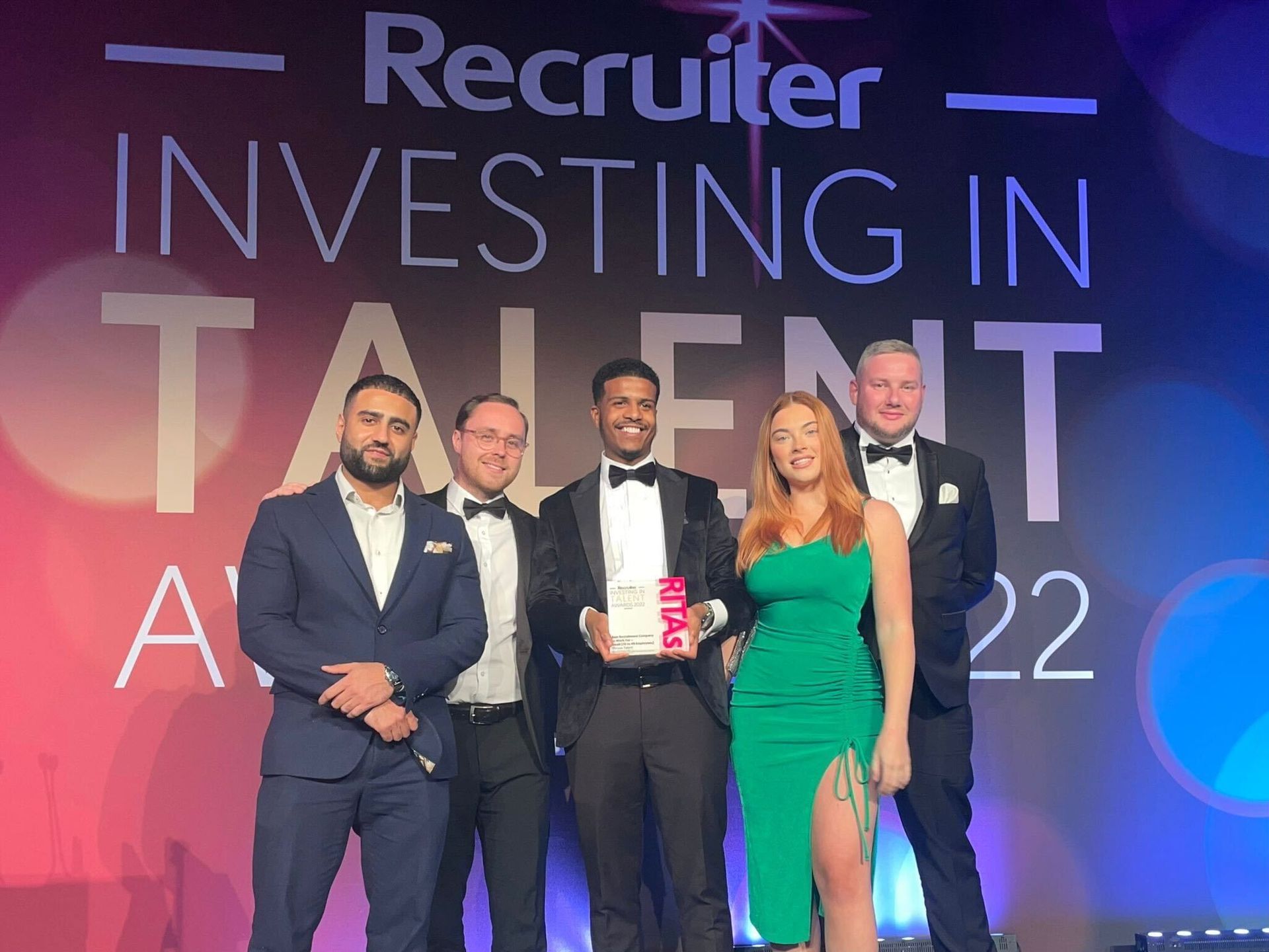 Group of people on stage holding award, under a banner that reads