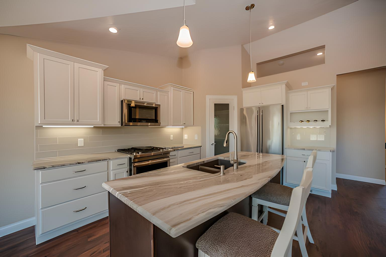 White kitchen with island, stainless steel appliances, and light-colored countertops renovated by quality affordable construction llc